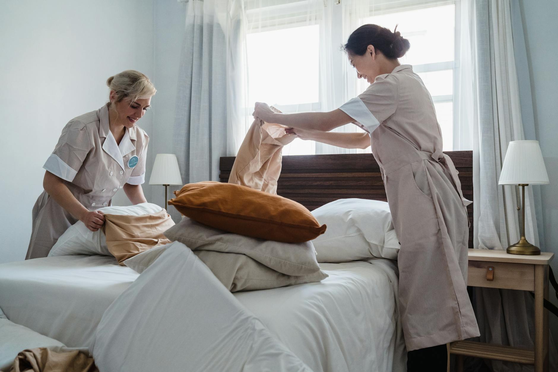 two women fixing a bed together