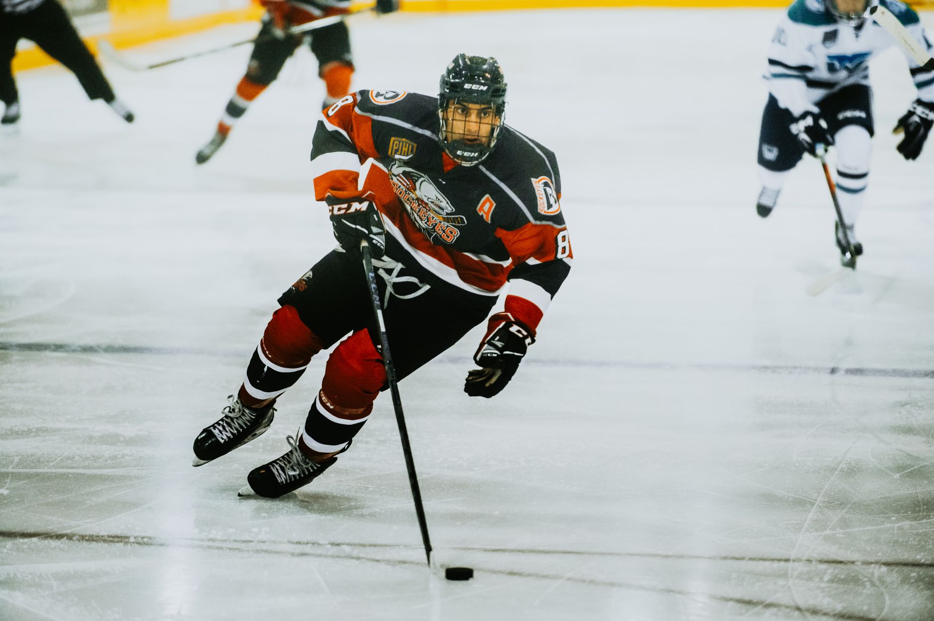 man in black and red ice hockey jersey playing hockey