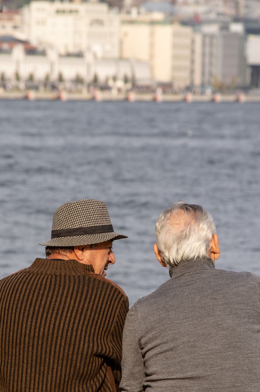 old men sitting near sea in city port