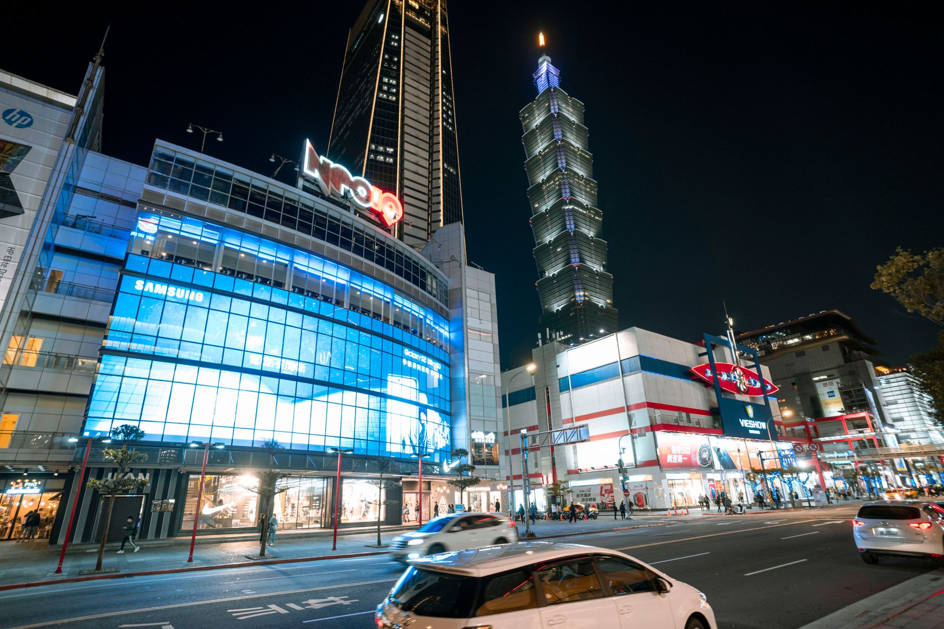 city with illuminated buildings and skyscrapers near road with cars